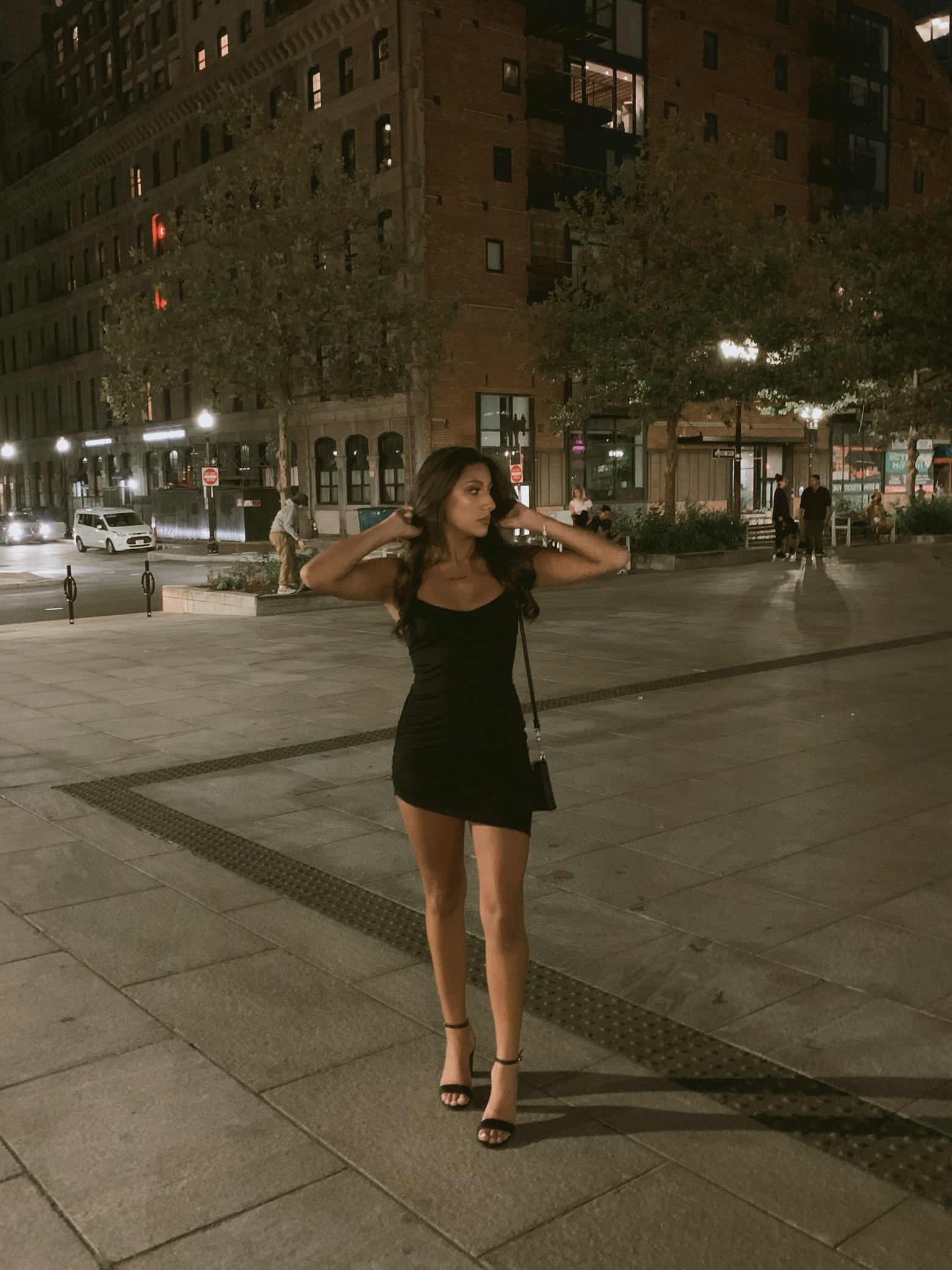 Barbara in a black dress in the city at night