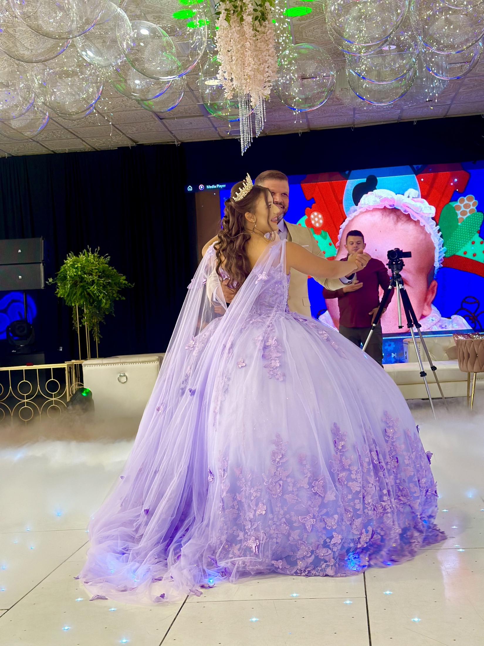 A celebratory dance in a lavender gown under event lighting